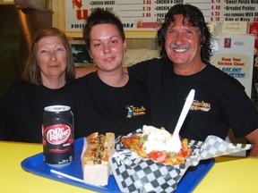 A Woodstock favourite, Fritzies celebrates 40 years in business this week. Left to right, Barb Vanniekerk, Tina Vandervecht and Perry Street restaurant owner Steve Charron posed for a picture in front of the famous Fritzies footlong, Fritz Royale fries and a cherry Dr. Pepper.  (TARA BOWIE, Sentinel-Review)