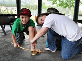 Ryan Lee, 10, and Ossie Treutler, 11, use a handmade bow drill to create dust that could be used for a fire during the First Nations Drill on the last day of the Wild Child specialty camp at Summer Fun on Friday, July 19. CORRIE DIMANNO/CRAG & CANYON/QMI AGENCY