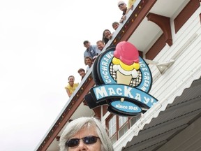 Cristina MacKay, matriarch of the MacKays, celebrates MacKay’s 65th birthday of being in business by eating an ice cream cone, while the MacKay clan looks down at the business below, July 21.