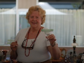 Lucienne Dolle of Montreal shows off a glass from her collection of antiques, which was on display during Morrisburg's annual Antiquefest on Saturday.
