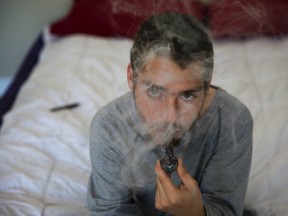 Medical marijuana user Michael Barron smokes marijuana from a glass pipe in his London apartment on Wednesday. DEREK RUTTAN/ The London Free Press /QMI AGENCY