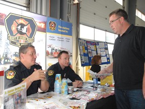 County of Grande Prairie Fire Services Fire Marshal Ken Atamanchuk (left) and member Billy Duncan, chat with Sanjel employee Kim Bentt about fire prevention and safety during Sanjel’s annual health and safety fair held at their location in Clairmont on Wednesday. (Jocelyn Turner/Daily Herald-Tribune)
