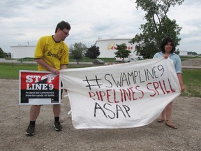 Zak Nicholls and Vanessa Gray hold up a banner outside the Enbridge site in Sarnia during a small demonstration held in June. Aamjwnaang and Sarnia Against Pipelines (ASAP) and others plan to hold a demonstration at noon Saturday on La Salle Line against Enbridge's Line 9 reversal plans. FILE PHOTO/ THE OBSERVER/QMI AGENCY