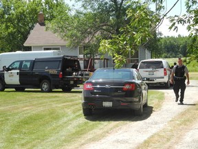 Six Nations Police spokesman Derrick Anderson walks down the lane of the home of homicide victim John Lickers, Sr. while OPP units from criminal investigation and identification continue inspecting the scene Friday, July 26, 2013. (SUSAN GAMBLE Brantford Expositor)