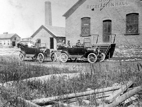Two of the 22 cars that called the Porcupine Camp home in 1915. Cars and drivers pose in front of the Dome Recreation hall, located on the Dome Mine property.