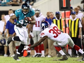 Jacksonville Jaguars running back Keith Toston moves the ball under pressure from New York Giants safety Will Hill in a 2012 NFL game. (REUTERS/Daron Dean)