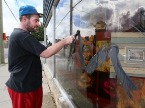 Doug Miller, of The Cleaning Brigade, uses a paint scraper to remove latex paint from a window of The Framery on Monday, July 29, 2013 in Owen Sound. Vandals painted several downtown businesses overnight Sunday. Police are investigating.  (The Sun Times/JAMES MASTERS/QMI Agency)
