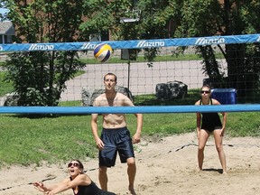 Tiffany Gagnon of Sandy Balls digs the ball during Pembroke Mixed Beach Volleyball League action at Fellowes. Looking are are Brad Hollett and Beth Turner of Smokin Aces.