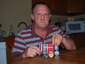 Canadian naval veteran Charles Stewart holds some of the medals he earned in the navy, in NATO and as a peacekeeper, at his home in St. Thomas. Stewart believes the Elgin Military Museum isn't involving enough veterans in HMCS Ojibwa. Ben Forrest/QMI Agency/Times-Journal