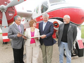 Mayor Bill Elliot, left, Minister Heather Klimchuk, Barry Marsden, and Byron Reynolds share a laugh as they inspect the logbook of Conair Firecat 567 during the official handover ceremony July 27.