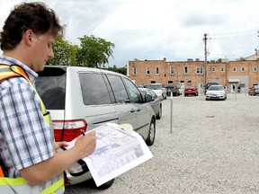 Chatham-Kent municipal engineering technologist Mark Ceppi studies the downtown parking lot at Fourth and Wellington streets in Chatham to prepare a report for council on turning the free parking space into a pay and display as well as permit parking area. VICKI GOUGH/ THE CHATHAM DAILY NEWS/ QMI AGENCY