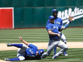 Blue Jays starting pitcher R.A. Dickey falls to the ground as third baseman Brett Lawrie (centre) couldn't make a catch during the fifth inning of their game against the Athletics in Oakland. (REUTERS/Stephen Lam)