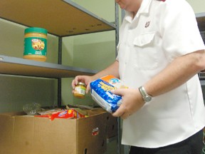 Major Daniel Roode with the Salvation Army Food Bank on 102 Street sorts through non-perishable food items to make a package for a needy family in the city on Tuesday morning. (Jocelyn Turner/Daily Herald-Tribune)