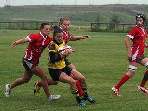 A member of the Calgary Hornets winces as she braces for a hit from the Strathcona Druids during a downpour at Lynn Davies Rugby Park last Saturday. The Druids came away with a huge 13-5 over the previously undefeated defending Premier champs. Photo by Shane Jones/Sherwood Park News/QMI Agency