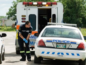 A paramedic speaks to a Portage la Prairie RCMP officer after an alleged gun shot victim was loaded into an ambulance at Long Plain First Nation, Friday. (Svjetlana Mlinarevic/Portage Daily Graphic/QMI Agency)