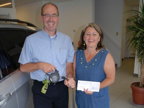 Cliff Lafreniere, left, owner of Pinewood Park Motors, presents Michelle Lafreniere, head of the dog park committee with a donation of $5,000 for the project.