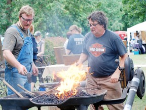 Blacksmiths David Borbely and  Walt Gardner of  Norfolk Forge, work on a piece of metal over an open fire during a public display at the 46th annual Rotary Friendship Festival this past weekend. (MONTE SONNENBERG Simcoe Reformer)