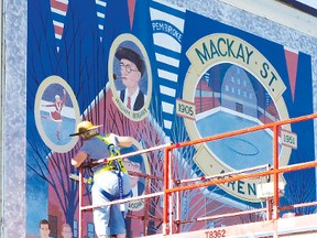 Artist Marillyn Saffery applies a clear coat to “The Mackay Street Arena 1905-1951” after completing repairs to the mural. The Pembroke Heritage Murals organization has been busy this year sprucing up its collection of outdoor murals.