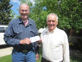 Dave Jackson, left, one of the four members of the Blue Ridge Lions Club and a West End Bus Society board member, presents a $1,000 cheque from the club to Ron Huntley, president of the West End Bus Society, at the Huntley’s Mayerthorpe home on Tuesday, July 30. Huntley said the society is seeking donation/sponsorship.
Ann Harvey | Mayerthorpe Freelancer