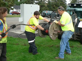 Alyssa Bedard, Paul Sequin and Phil Lazarou, with the city's parks and recreation department, roll up part of 5,000 feet of buried electrical cable used during Summer in the Park festivities this past weekend.