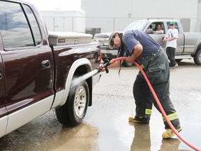 Justin Nepoose hoses out the wheel well of a pickup during a fundraiser carwash for the Maskwacis Fire Department.