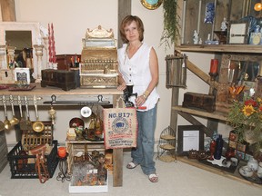 Judi Olson stands next to one of the many unique displays in her new shop. An impressive variety of antiques, trinkets, and collectables are on display, including stain glass art and cabinetry work done by her husband, Bruce.