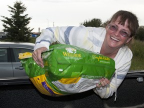 TAYLOR WEAVER HIGH RIVER TIMES/QMI AGENCY
Colleen Brown helps unload dog food on Tuesday night as High River residents made their way to the Super 8 parking lot to pick up free dog food which has been donated to support the town.