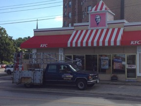 A worker replaces a window that was kicked in Saturday morning at the KFC restaurant in Owen Sound. (DENIS LANGLOIS/QMI AGENCY)