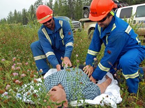 Grande Prairie Focus party chiefs Daelan Kusyk (left) and Jeff Davis start the first aid process on their fallen co-worker “Ben,” during a mock emergency drill on Friday August 9, 2013. The team played out the scenario with help from STARS, roughly 25 kilometres south of Grovedale. (Elizabeth McSheffrey/Daily Herald-Tribune)