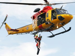 A search and rescue technician with 424 Transport Search and Rescue Squadron at 8 Wing/CFB Trenton, Ont. hoists a mock victim who jumped off in the Bay of Quinte in the area of Snake Island, just east of Belleville, Ont., up to one of the squadron's CH-146 Griffon helicopters during a training exercise Sunday, Aug. 11, 2013.     JEROME LESSARD/The Intelligencer/QMI Agency