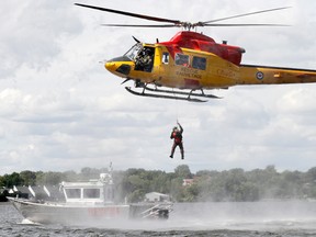 A search and rescue technician with 424 Transport Search and Rescue Squadron at 8 Wing/CFB Trenton, Ont. is being hoisted back up to one of the squadron's a CH-146 Griffon helicopters from Quinte Search and Rescue's (QSAR)'s primary vessel, the Bruce A. Sutcliffe, on the Bay of Quinte in the area of Snake Island, just east of Belleville, Ont., during a training exercise Sunday, Aug. 11, 2013.  JEROME LESSARD/The Intelligencer/QMI Agency/File photo