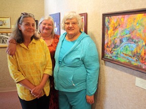 Members of the Porcupine Art Club, from left, Silvana Jasaitis, Laura McCurdy and Elizabeth O’Connor are among the artists whose works are being showcased in the gallery this month at Centre culturel La Ronde. The painting shown here is O’Connor’s artistic depiction of last year’s Timmins 9 forest fire. The exhibition runs until the end of August.