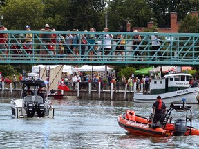 Boats slide underneath the Wallaceburg walking bridge on Saturday, as people on the bridge look on during the Wallaceburg Antique and Motor Boat Outing.