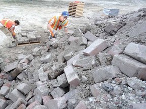 At the municipal landfill site Monday, Aaron Erb-Ohnsorge, left, and Collin Dunn clean and stack some of the thousands of bricks recovered from the reconstruction of Shakespeare St. (SCOTT WISHART The Beacon Herald)