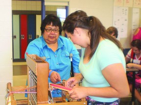 Laura McLaughlin (L) demonstrates how to make the woven l’Assomption Sash. Jordan Small/ Cold Lake Sun