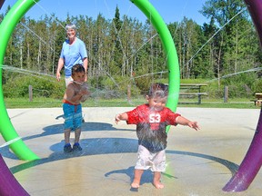 A Blue Ridge grandmother, Lorraine Mogensen, watches and smiles as, from left, Armand Pelchat, 3, and Hector Pelchat, 15 months, have fun at the Berry Nice Spray Park in Blue Ridge on Tuesday, Aug. 6.