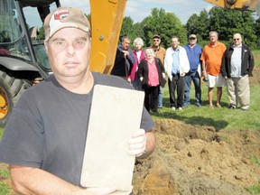 Larry Polfliet, of La SaLette, displays a footstone that was retrieved from a 19th-century Catholic cemetery northeast of Delhi. In back, from left, are Dean Knight of Kitchener, Marcia Parker of Oregon, Marie Shull of Simcoe, John Shull of Simcoe, Dan Walker of Delhi, Keith Markel, of Burford, Tom Kramer of Delhi and Don Kramer of Otterville. (MONTE SONNENBERG Simcoe Reformer)