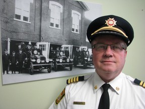 John Kingyens has been appointed chief of the Sarnia Fire Rescue Service, effective Aug. 19. Chief Kingyens stands next to a 1920s-era photo of a former city fire hall on George Street. Sarnia, On., Aug. 14, 2013  PAUL MORDEN / THE OBSERVER / QMI AGENCY