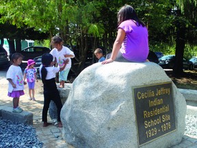 Children play on the newly erected monument to Cecila Jeffrey Residential School victims on the site where the school used to stand.