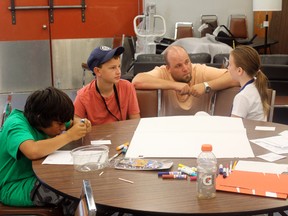 Biz Kinds campers Ethan Cadieux, Max MacGillivery and Amelie Grahan brainstorming a new invention with guidance from Andrew Koch from the Northern Ontario Youth Entrepreneurship Initiative.