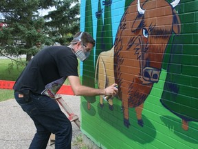 Toronto-based graffiti artist Uber5000 works on a mural on the side of the Father J.A. Turcotte School Tuesday. ANDREW BATES/TODAY STAFF