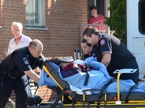 Paramedics tend to a woman on a stretcher in the parking lot of Bayfield Manor, located on 10th St. E. near the intersection with 9th Ave. E. (JAMES MASTERS The Sun TImes)