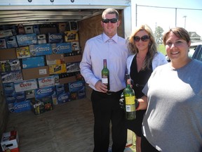 Darren and Jaimie D'Hondt stand with Mandie Marques in front of a collection of empty beer and wine bottles collected at the McLaughlin Sports Park on Saturday. Marques organized the bottle drive to help raise money for the D'Hondt family who recently lost their home and all of their belongings in a fire. (SARAH DOKTOR Delhi News-Record)