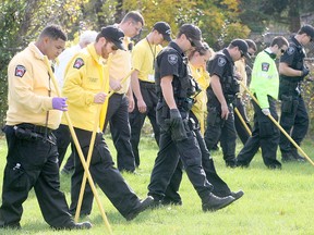 Kingston police emergency response unit officers join with community policing volunteers in searching Starr Reid Park, behind the apartment buildings on Briceland Street in a hunt for any evidence left behind by the suspects fleeing a 2010 murder.
Michael Lea The Whig-Standard