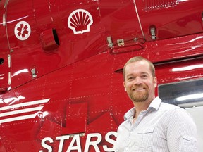 Chris MacCallister stands in front of a STARS helicopter. MacCallister will spend time on an island in a fundraising effort for STARS on Sept. 12. He hopes to raise $100,000 for their STARS Rescue on the Island. (Submitted Photo)