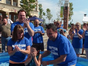 Eight-year-old Aislin Carrol is baptized by her mother Krissy, pastor Brian Beattie and father Dave Carrol in the second annual community baptism ceremony mounted by five churches in Harmony Square on Sunday afternoon. (MICHAEL-ALLAN MARION Brantford Expositor)