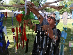 Stained glass maker Karen Thomas hangs necklaces for display at Sunday’s women’s art show in City Park. (Elliot Ferguson The Whig-Standard)