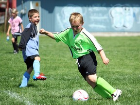 Under-8 division player Chase Meunier, foreground, of Ontario Power Generation pounces on a loose ball in front of the net for a goal as Makai Vaillancourt of the Kiwanis Club Sharks looks on Saturday during the North Bay Youth Soccer Club's Tim Hortons Jamboree at ONR Field. JORDAN ERCIT/The Nugget