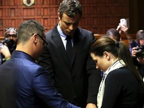 Olympic and Paralympic running star Oscar Pistorius, centre, holds hands with his sister Aimee, right, and brother Carl ahead of court proceedings at the Pretoria Magistrates court, August 19, 2013. (REUTERS/Siphiwe Sibeko)