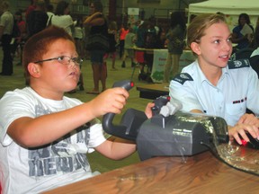 Cadet Victoria Lambert teaches 7-year-old Nicolas Cobiness Paul how to use a flight simulator during the 2011 mass registration at the Kenora Recreation Centre. 
FILE PHOTO/DAILY MINER AND NEWS